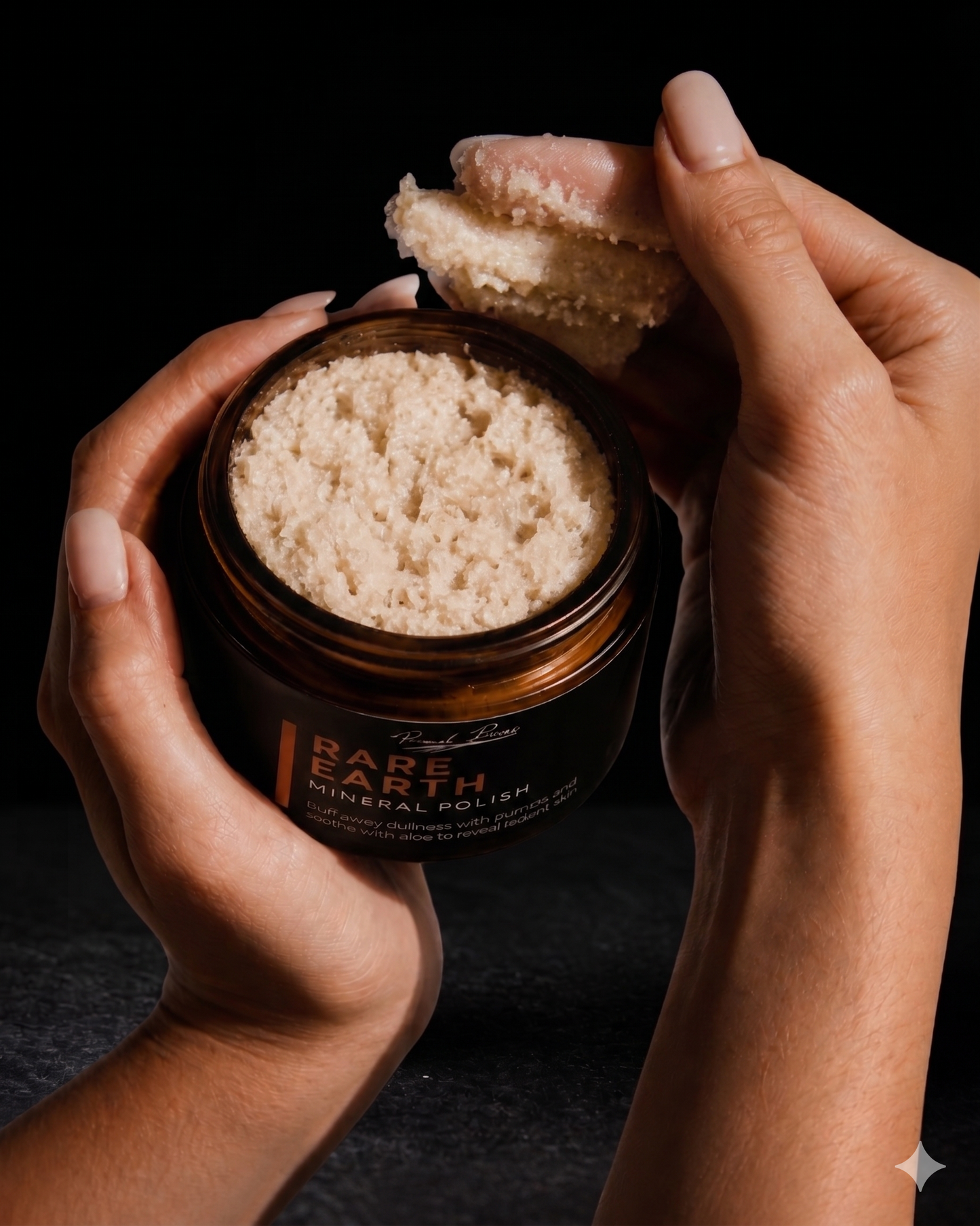 Jar of 'Rare Earth' mineral polish held by hands against a dark background