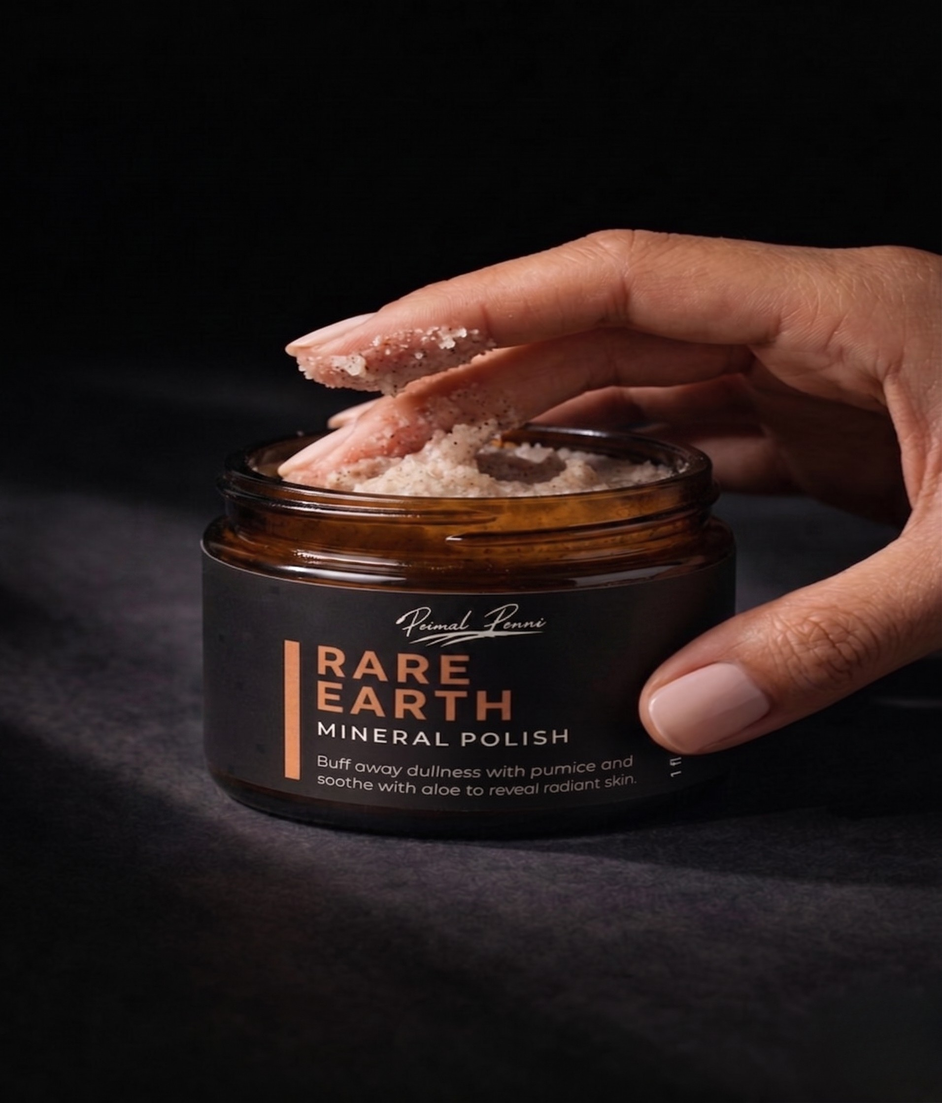 Hand holding a jar of 'Rare Earth Mineral Polish' against a dark background
