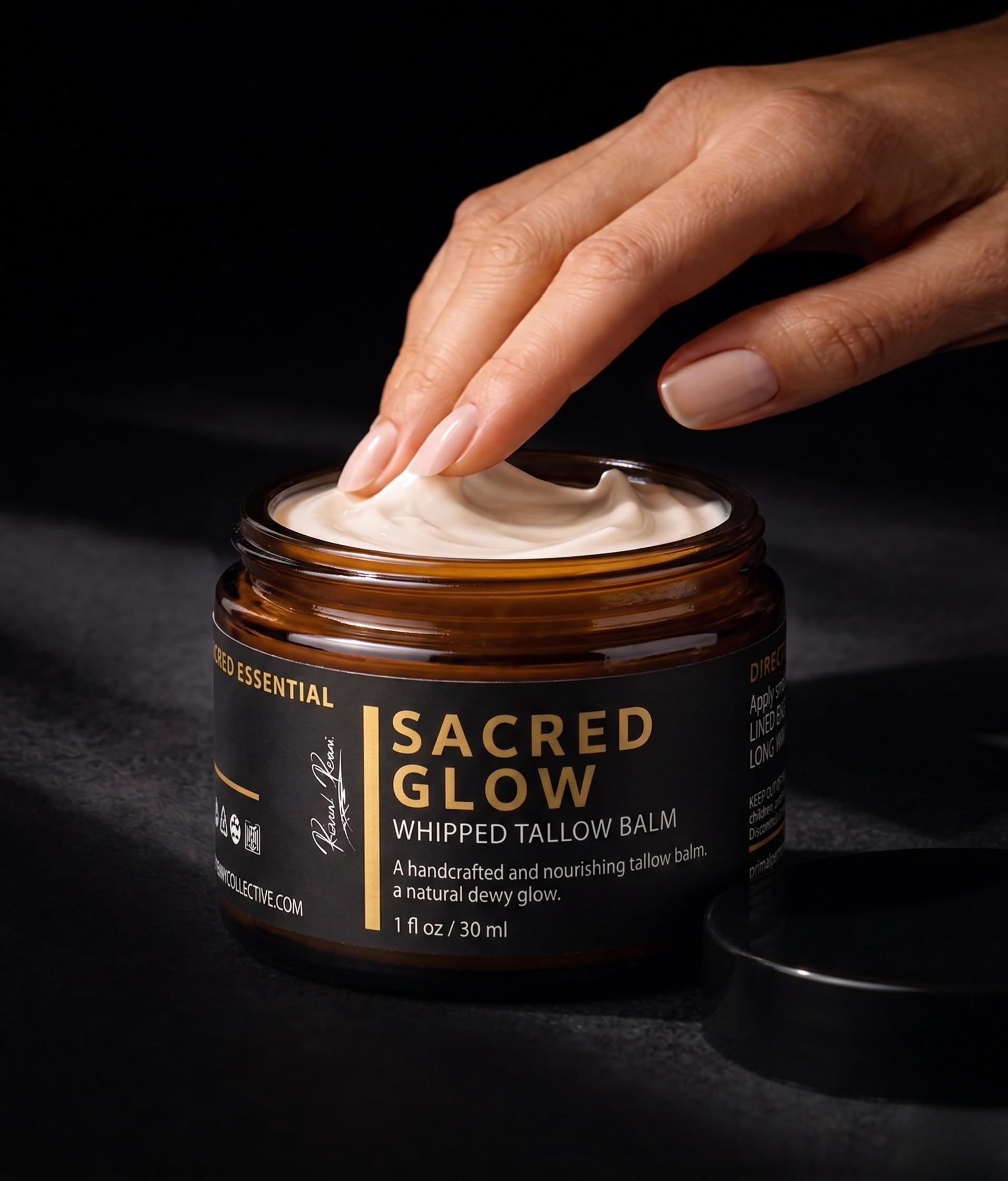 Hand applying whipped tallow balm from a jar labeled 'Sacred Glow' on a dark background